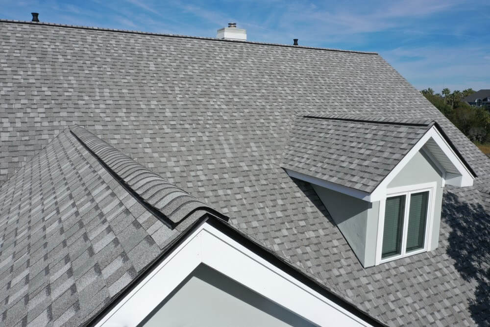 Close-up of a gray architectural asphalt shingle roof with a dormer window