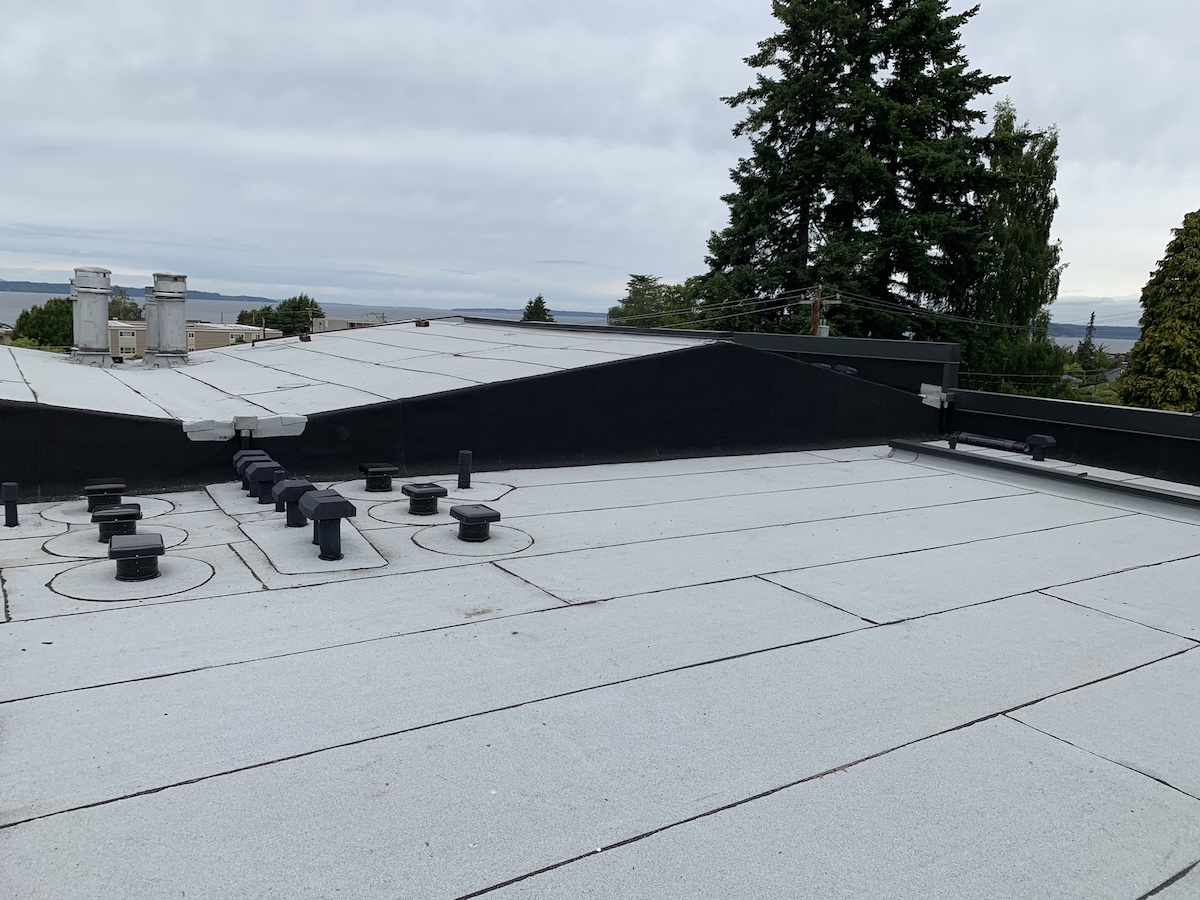 Flat modified bitumen torch-down roof with vents overlooking the water