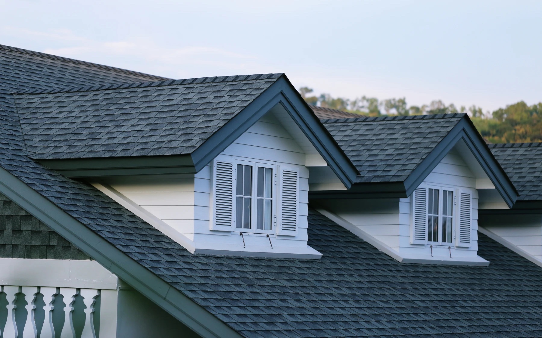 Close-up of a gray architectural shingle roof with dormer windows on a home