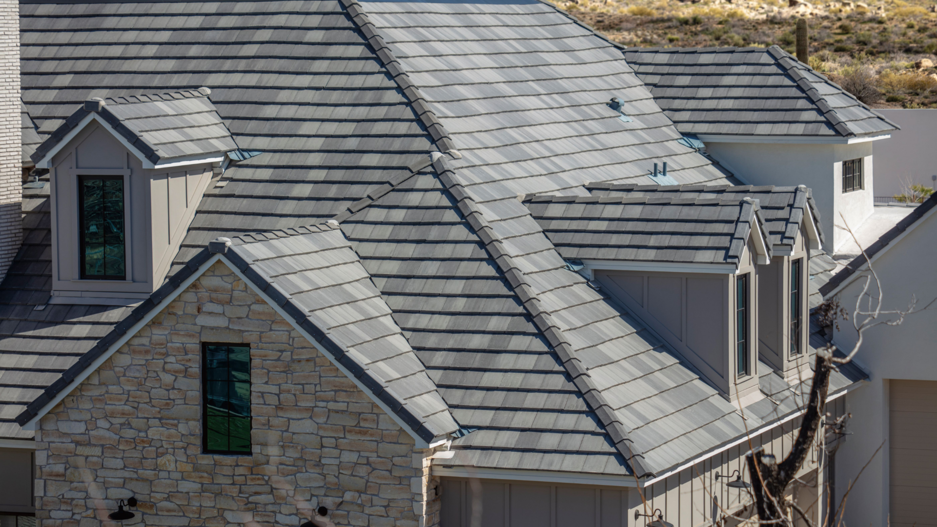 Aerial view of a gray concrete tile roof on a large home with dormers