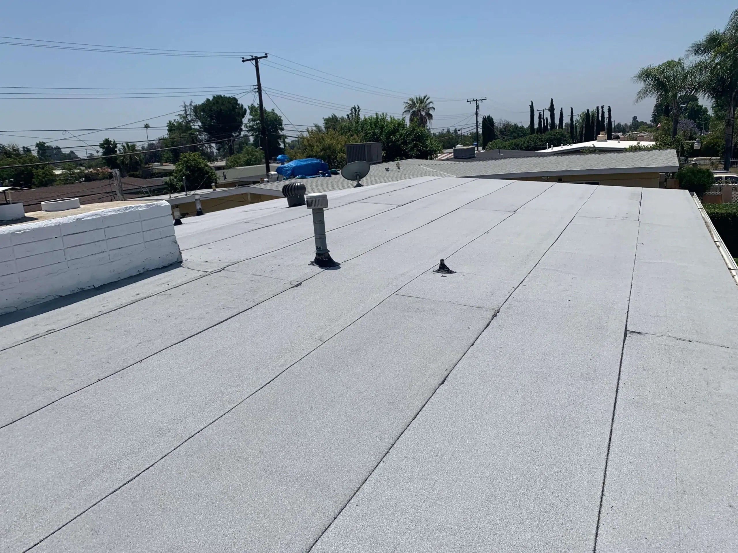 Flat modified bitumen roof with vents overlooking a residential neighborhood